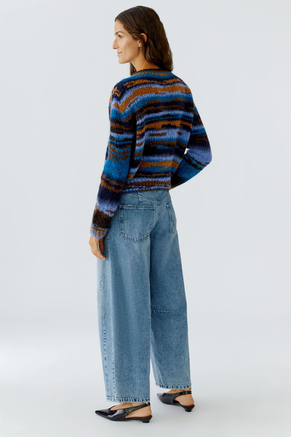 Femme portant un chandail en tricot rayé à col rond multicolore, associé à un jean, vue de dos.