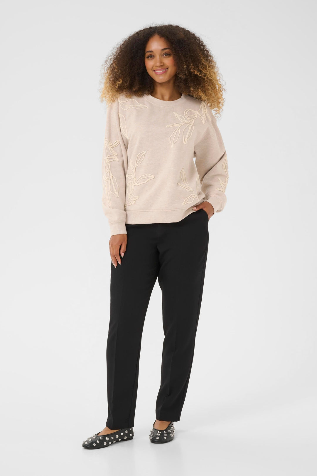 Femme portant le Chandail Lovisa en coton ouaté à broderies ton sur ton pour un look décontracté et élégant, avec motif floral délicat.