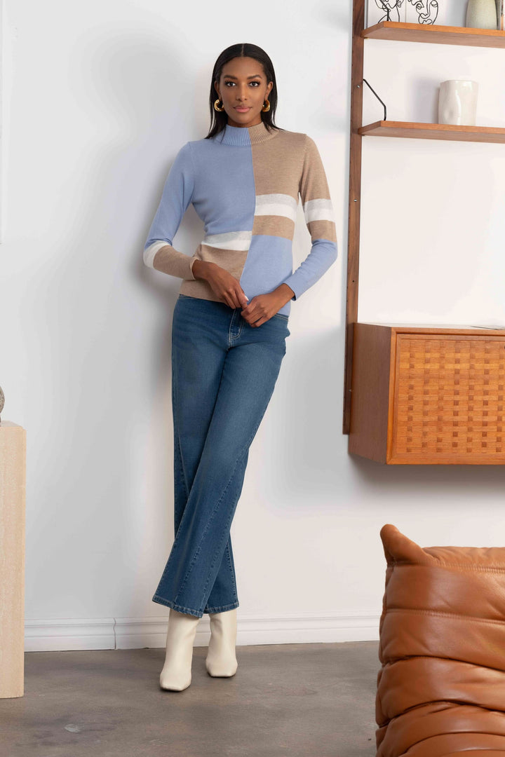 Femme portant un chandail à col montant et blocs de couleur avec jean et bottines blanches.