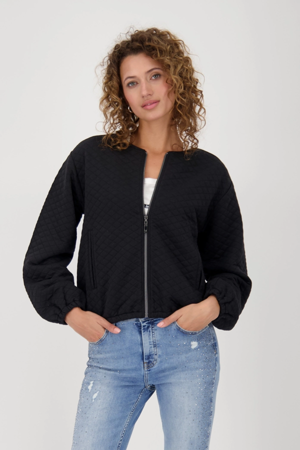 Veste matelassée avec poches, coupe moderne, manches bouffantes, motif losanges, femme posant, élégante et décontractée.