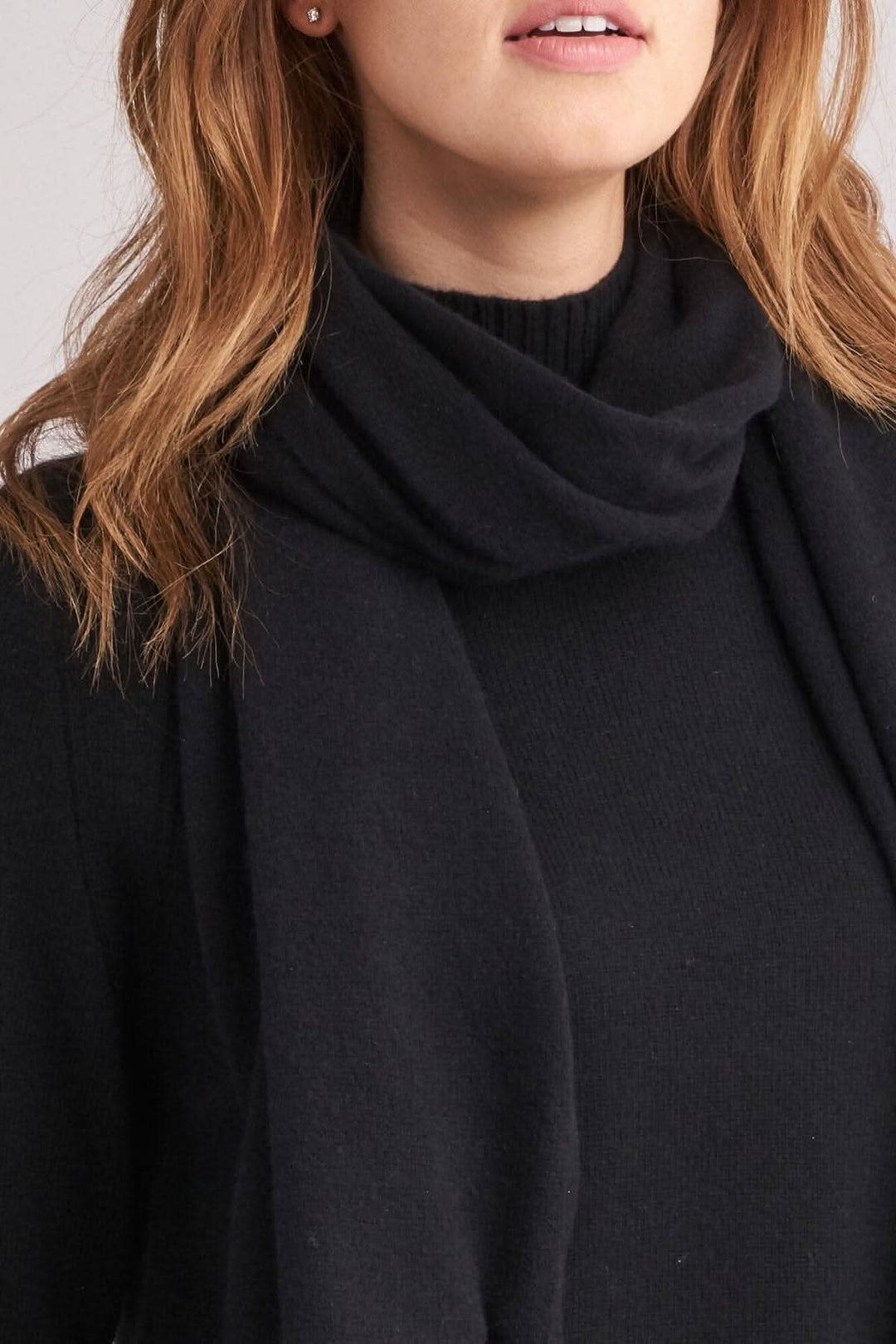Écharpe en cachemire noire portée avec un pull, mettant en valeur sa douceur et sa légèreté.