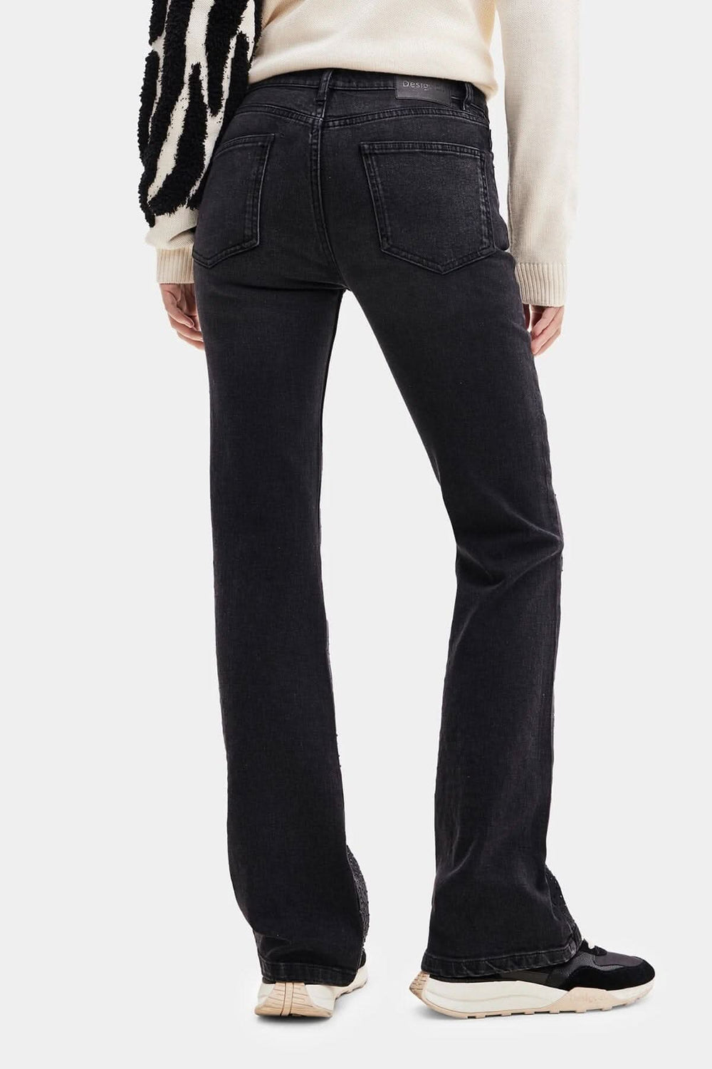 Pantalon noir taille haute avec coupe large et poches, porté de dos par une personne, parfait pour un look décontracté.