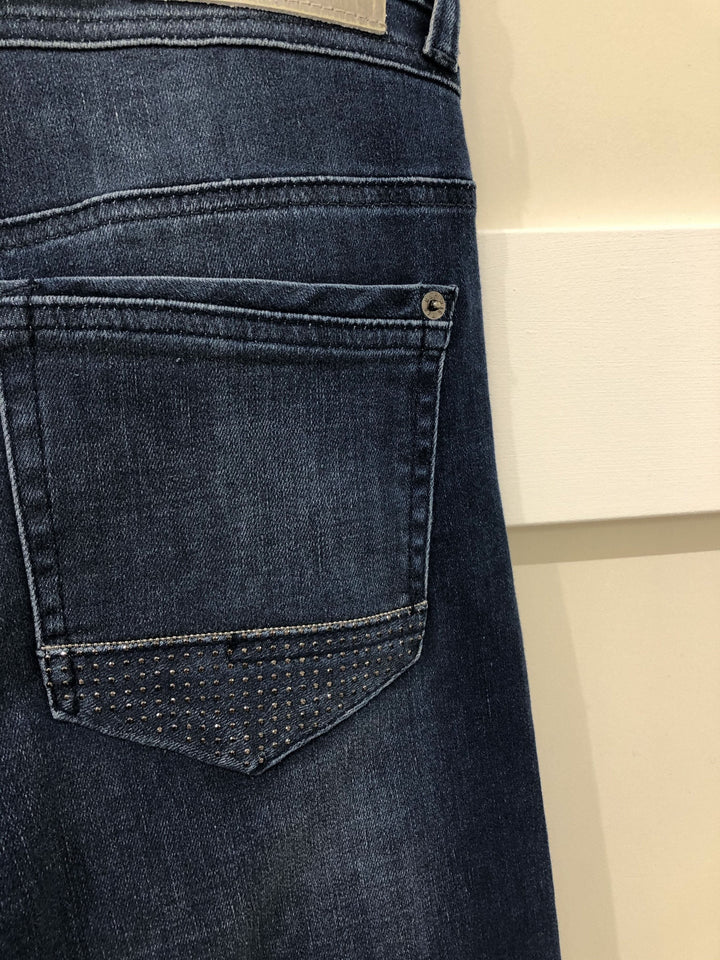 Détails d'un jean bleu délavé avec des brillants sur la poche arrière, modèle Jean Rich.
