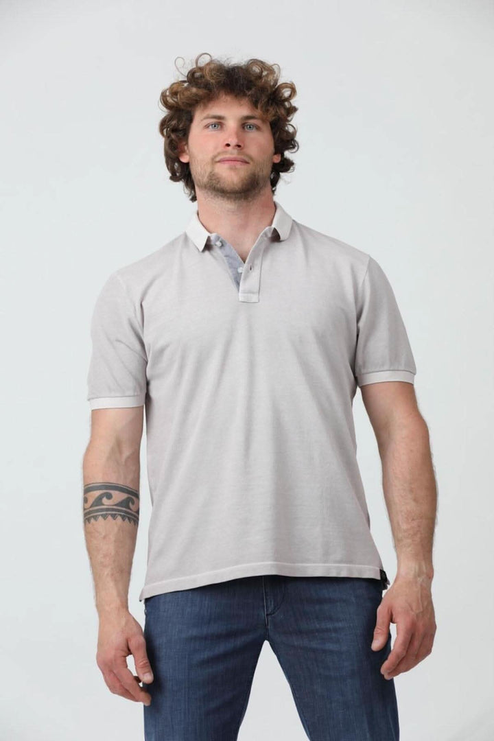 Homme portant un polo à manches courtes en coton piqué, couleur gris clair, avec col côtelé et fermeture à boutons.